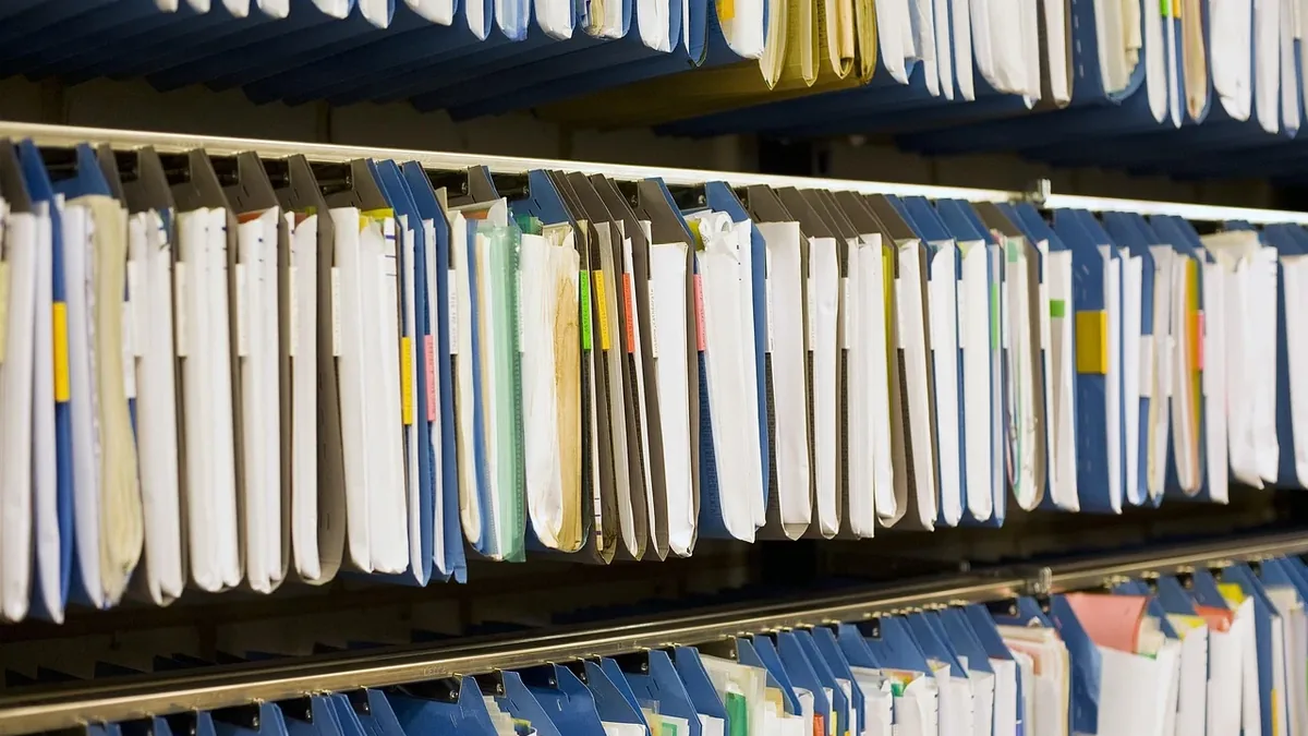 A row of hanging file folders containing documents, with each folder labeled and organized in a filing cabinet.
