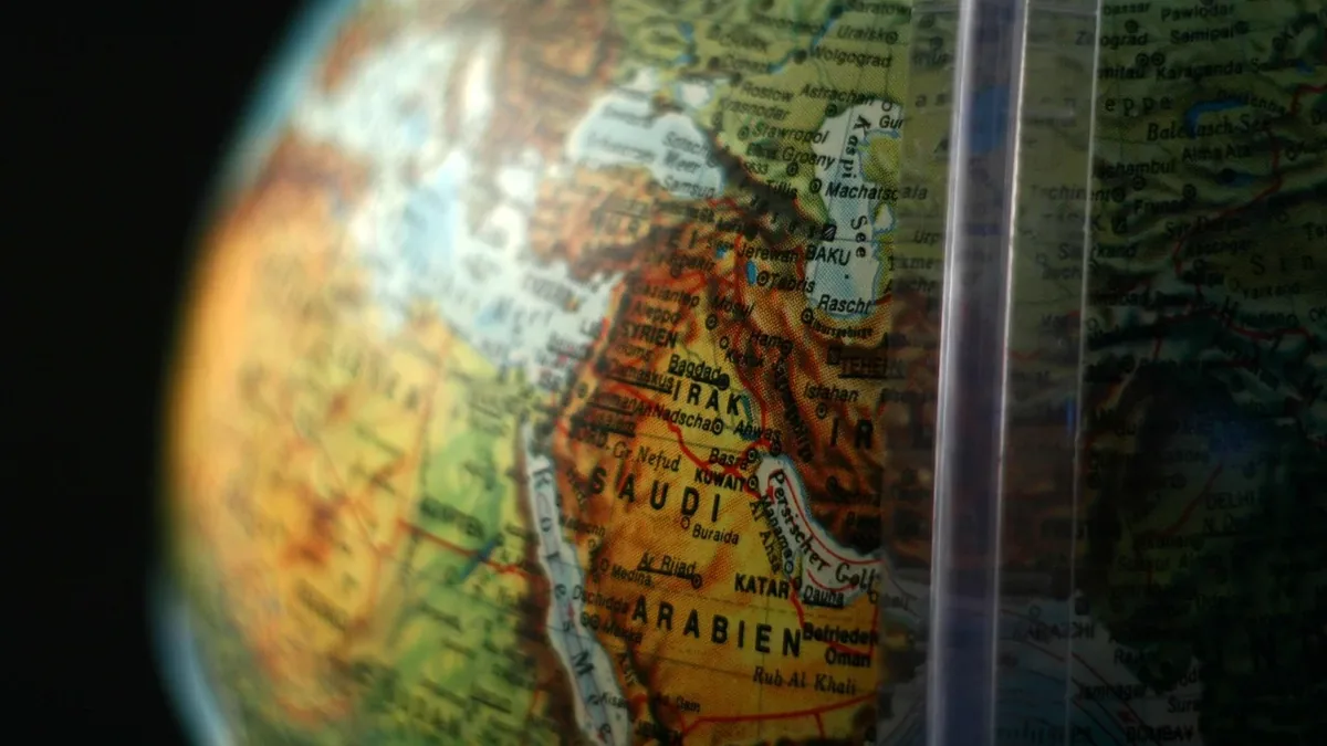 A globe with a map of the Middle East, featuring the countries of Saudi Arabia, Yemen, Oman, United Arab Emirates, Qatar, Bahrain, Kuwait, I