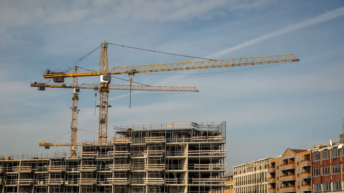 A construction site with multiple buildings under development, featuring scaffolding and cranes.