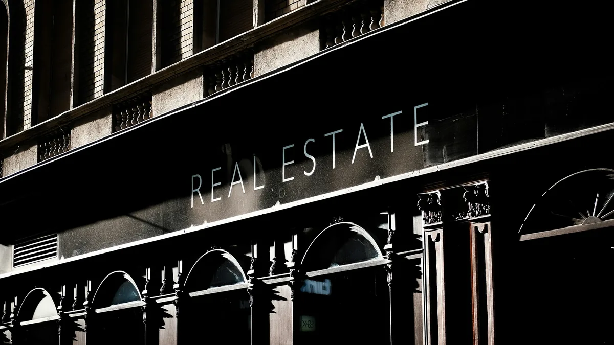 A building with a sign that reads "REAL ESTATE" and features a row of arches and columns.