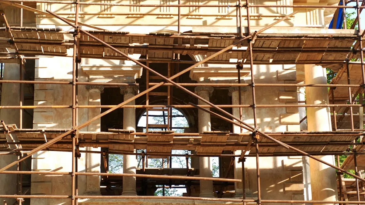 A building under construction, with scaffolding and wooden planks visible.